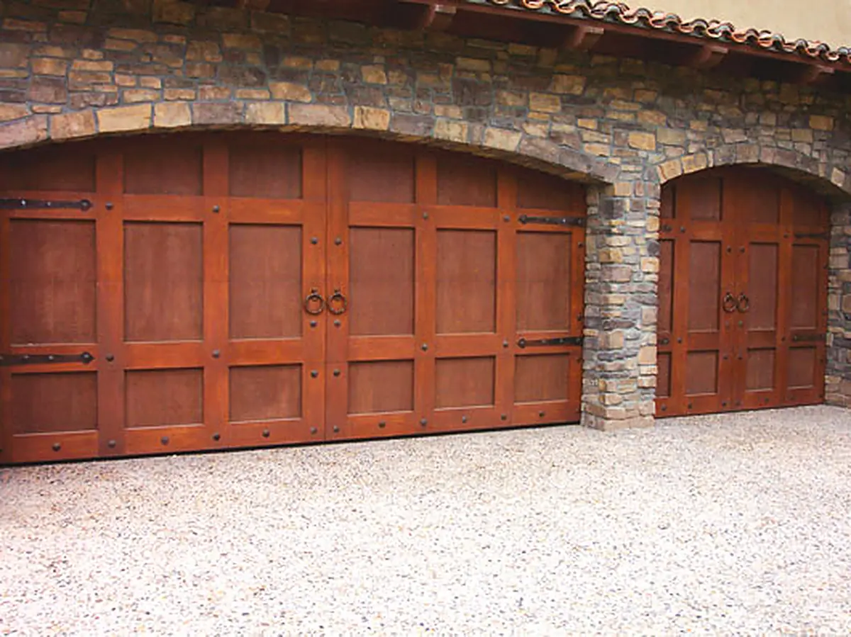 Custom wood carriage-style garage doors under stone arches